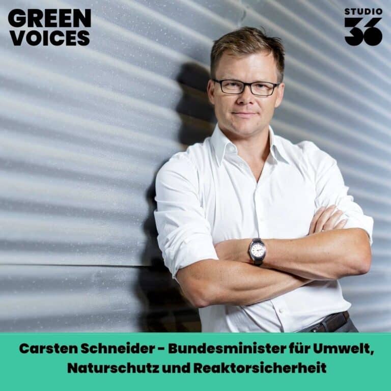 Carsten Schneider, Bundesminister für Umwelt, vor einer strukturierten Wand, lächelt in die Kamera.
