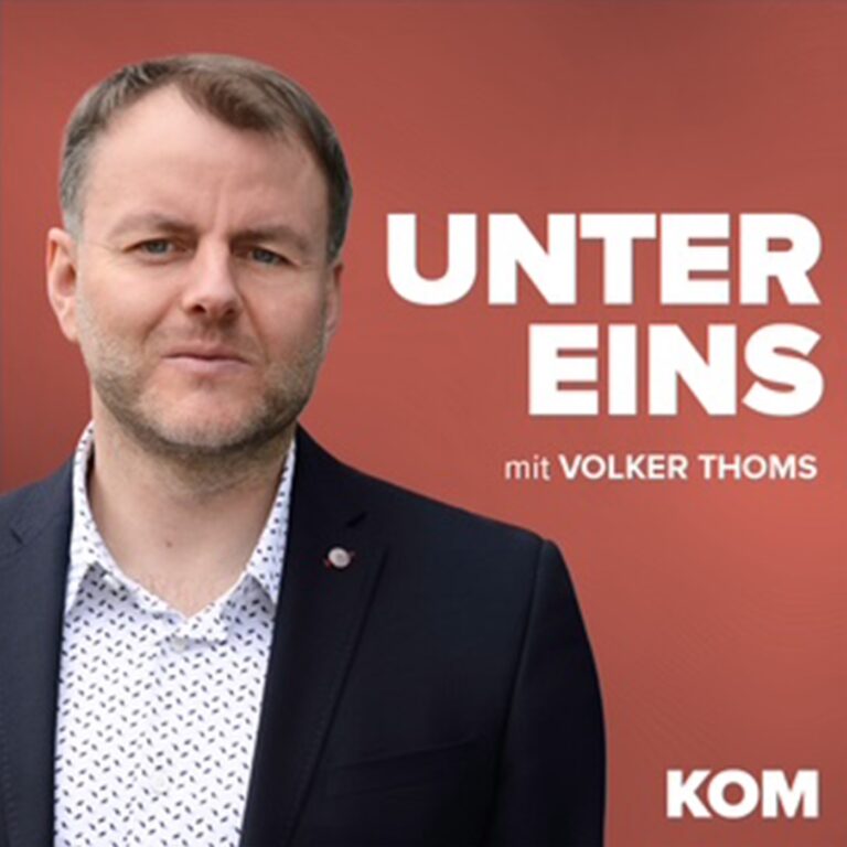 Mann mit kurzem Haar und Anzug, lächelt vor einem roten Hintergrund, Titel: "Unter Eins mit Volker Thoms".