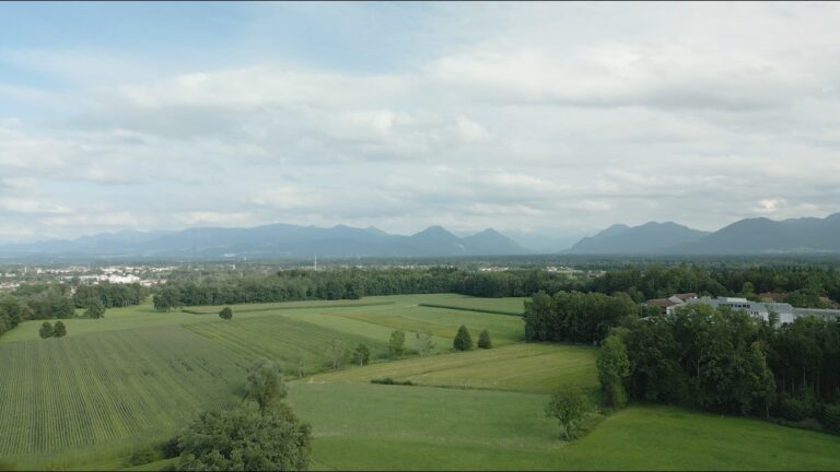Landschaft mit grünen Feldern und Bergen im Hintergrund, aufgenommen aus der Luft bei DRV Bad Aibling Rheumaklinik.